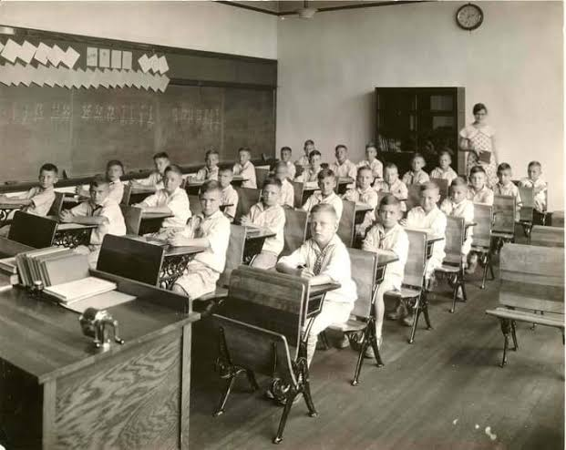 Rows of wooden desks in an early classroom